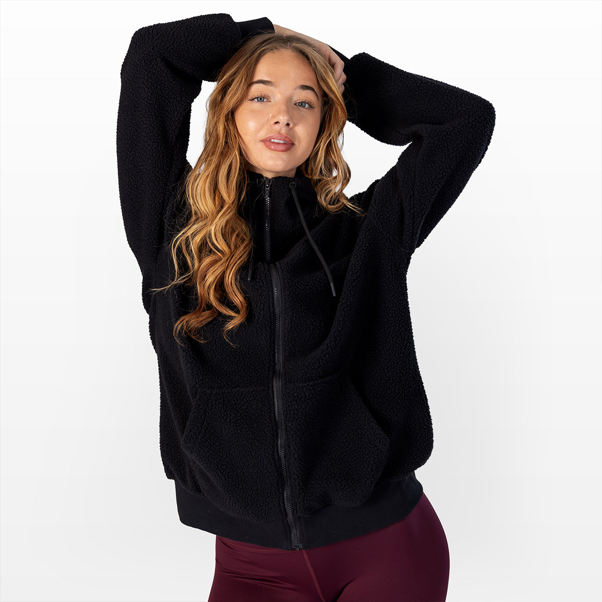 Black sherpa zip-up hoodie with zip front and hood, arms raised