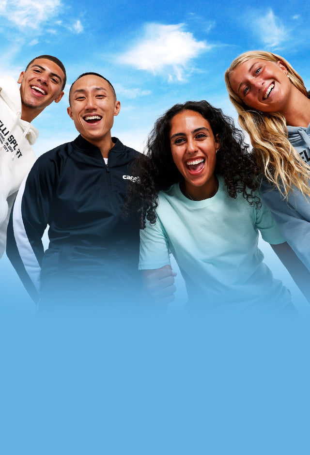 Four people posing together with a blue sky background