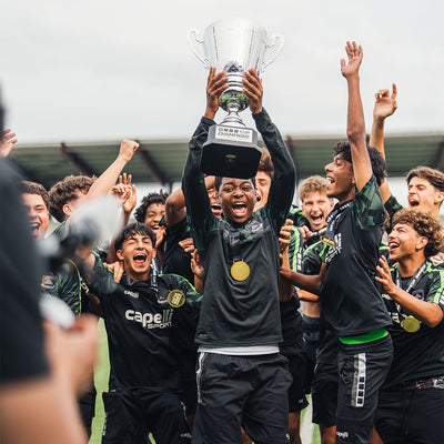 Group of soccer players celebrating with a trophy on a sports field