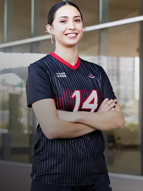 Woman wearing a Capelli Sport Volleyball jersey with the number 14 in an indoor setting