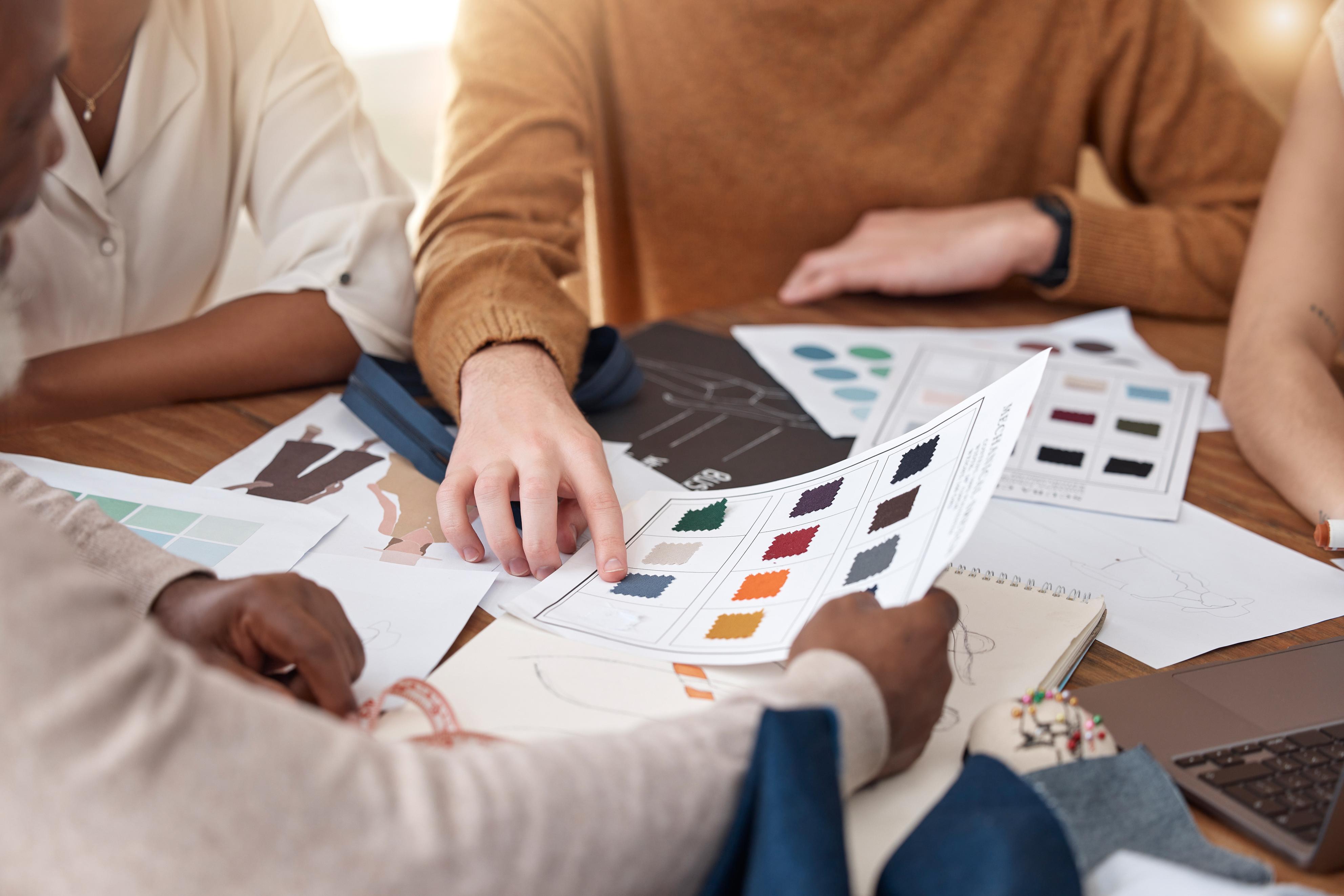 People working on design projects with color swatches and sketches at a table.