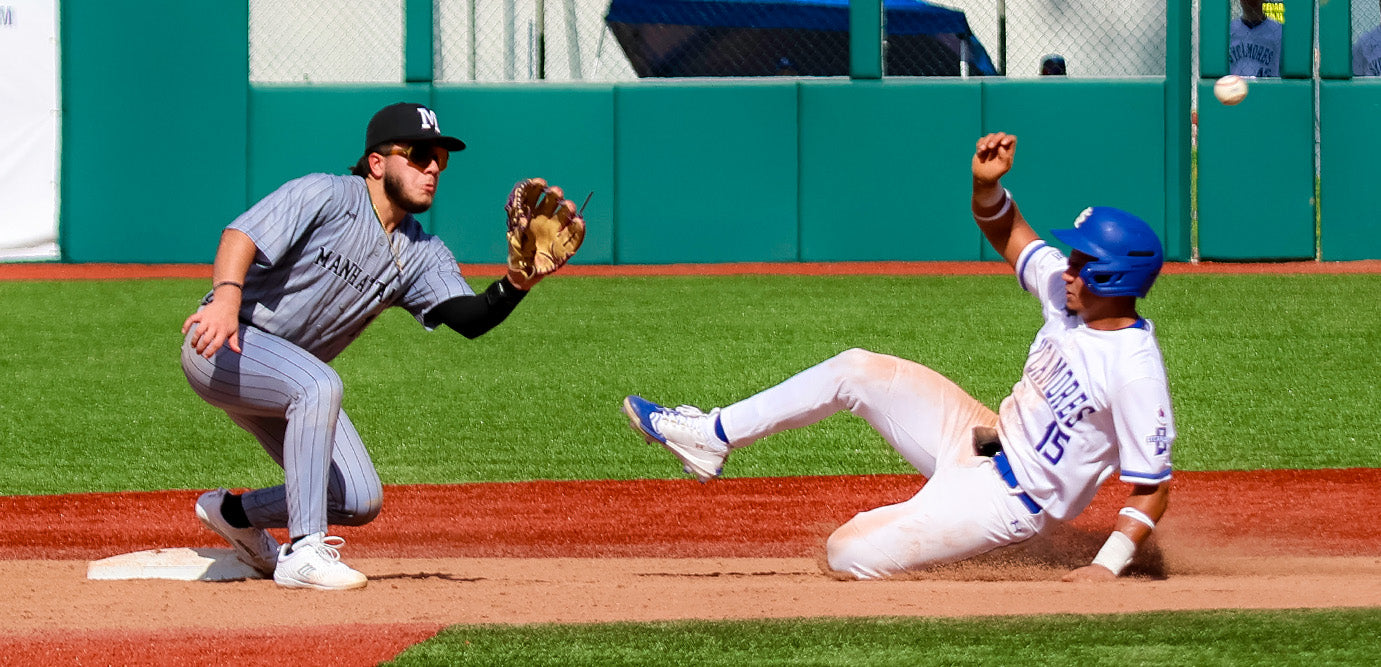 Baseball player sliding into a base while another player tries to tag him out on a baseball field.