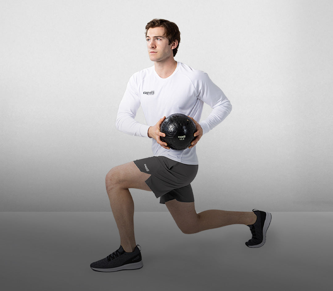 Man performing a lunge with a medicine ball on a gray background