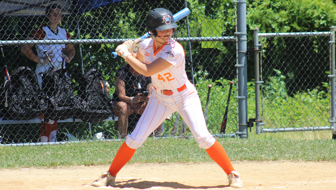 Baseball player in a white and orange uniform with number 42, holding a bat, on a baseball field.